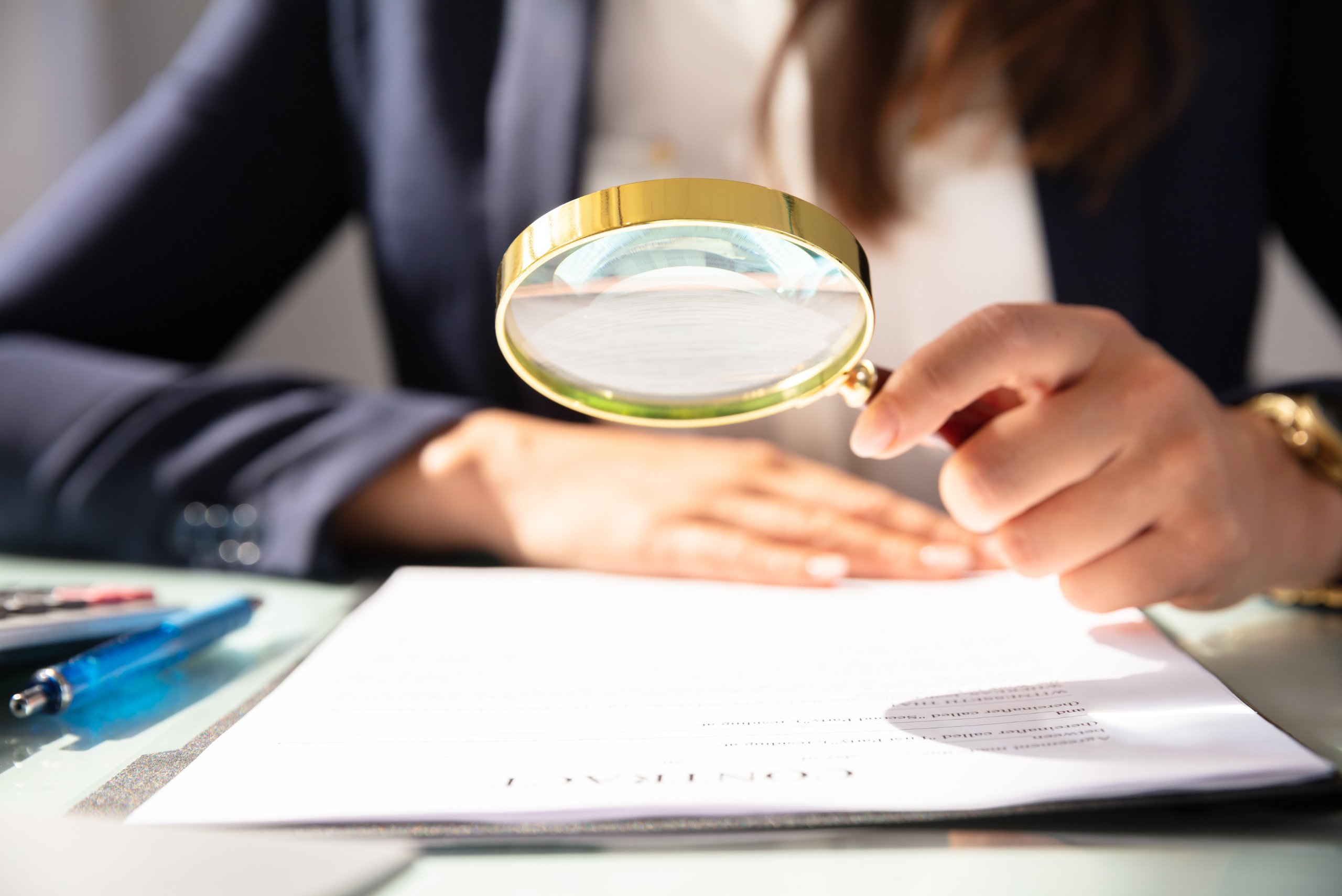 Woman Looking at Contract Through Magnifying Glass Woman Looking at Contract Through Magnifying Glass