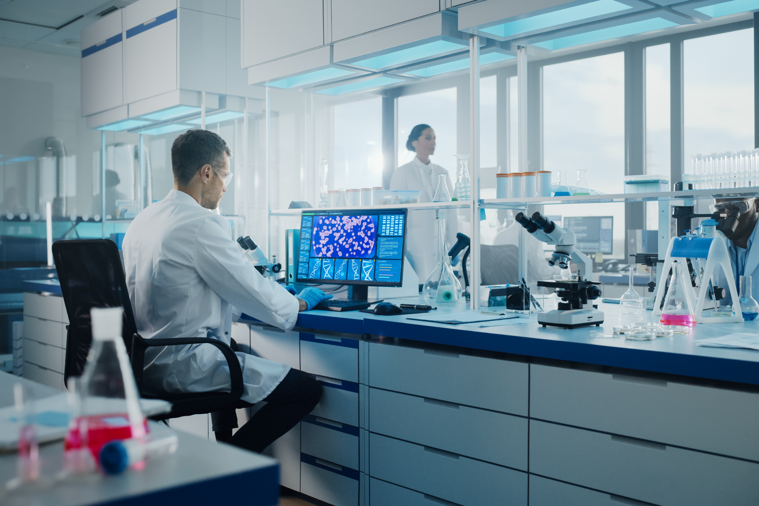 Man in white coat working on a computer in a laboratory